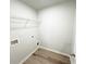 Functional laundry room featuring white walls, wood-look flooring, utility connections, and wire shelving for storage at 5342 Legacy Trl, Douglasville, GA 30135