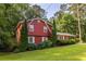 Red two-story home featuring neat landscaping, mature trees, and white-trimmed windows at 1102 Waverly Dr, Lawrenceville, GA 30046