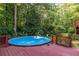 Above-ground pool with a wooden deck in a backyard setting, surrounded by lush greenery and mature trees at 1102 Waverly Dr, Lawrenceville, GA 30046