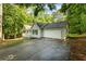 A beautiful single story home with an attached garage and a long driveway is surrounded by lush trees at 1154 Pinebrook Rd, Auburn, GA 30011