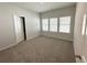A bright bedroom with three windows, a neutral carpet, and painted in a soothing light gray at 5295 Greenway Dr, Villa Rica, GA 30180