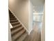 A hallway with carpeted stairs, hard flooring, and a view of the open living area at 5295 Greenway Dr, Villa Rica, GA 30180