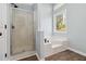 Bathroom featuring glass shower, tub with tile surround and light filled window at 231 Clarion Rd, Lawrenceville, GA 30043