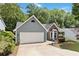 Gray home featuring a two-car garage, nicely kept lawn, and mature trees in the background at 231 Clarion Rd, Lawrenceville, GA 30043