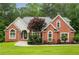 Charming red brick home featuring an immaculate lawn, arched windows, and professional landscaping at 7406 Cherry Blossom Way, Winston, GA 30187