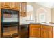 Well-equipped kitchen featuring wood cabinets, black appliances, granite countertops, and an arched opening at 7406 Cherry Blossom Way, Winston, GA 30187