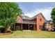 Spacious backyard showcasing a brick home with a wooden deck, staircase, and well-manicured lawn and some landscaping at 9157 Golfview Cir, Covington, GA 30014