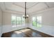 Sunlit dining room featuring hardwood floors, decorative chandelier, and large windows at 9157 Golfview Cir, Covington, GA 30014