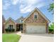 Charming stone and siding home featuring a two-car garage and manicured lawn at 9157 Golfview Cir, Covington, GA 30014