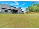 A sprawling backyard offers ample space with a modern gray home and lush greenery under a bright, blue sky at 157 Palisade Ne Dr, Rydal, GA 30171