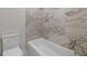 Well-lit bathroom featuring a white tub with elegant marble-like tiled walls and a toilet at 157 Palisade Ne Dr, Rydal, GA 30171