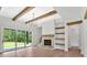 Bright living room featuring a stone fireplace, wood beams, hardwood floors, and sliding glass doors to the yard at 157 Palisade Ne Dr, Rydal, GA 30171