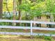 View of a single-story home with brick exterior and dark shutters seen through a white wooden fence at 161 E 78 Hwy, Temple, GA 30179