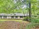 Rear view of a single-story home with painted brick and dark shutters surrounded by lush trees and vegetation at 161 E 78 Hwy, Temple, GA 30179
