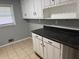 This kitchen features white cabinets, black counters, and tiled floors at 2903 Santa Barbara Dr, Decatur, GA 30032
