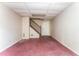Unfinished basement with a staircase, a door, and outdated red carpet, ready to be remodeled at 3391 Quail Hollow Trl, Snellville, GA 30039