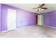 Bedroom with purple walls, carpet flooring, ceiling fan with a light, and doors leading to other rooms at 3391 Quail Hollow Trl, Snellville, GA 30039