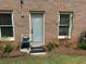 Backdoor entry with brick wall, two windows, landscaping and an outdoor water hose reel at 1305 Lake Forest Ln, Mcdonough, GA 30253