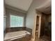 Bright bathroom featuring a soaking tub, shower, and a large window for natural light at 1305 Lake Forest Ln, Mcdonough, GA 30253