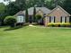 Beautifully landscaped front yard with mature trees, lush lawn, and classic brick home at 1305 Lake Forest Ln, Mcdonough, GA 30253