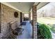 Inviting front porch with brick columns, rocking chair and a view of the surrounding landscape at 689 Hardin Rd, Temple, GA 30179