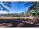 View of the surrounding land featuring fenced areas and mature trees under a blue sky at 689 Hardin Rd, Temple, GA 30179