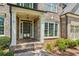 Close-up of a brick home's front porch with white columns, a dark door, and manicured landscaping at 1320 Magnolia Park Cir, Cumming, GA 30040