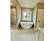 Modern bathroom featuring freestanding tub, tiled floors, glass enclosed shower, and natural light at 1111 Lake Varner Dr, Covington, GA 30014