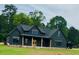 Beautiful two-story home boasts a black exterior, spacious yard and wooded backdrop at 1111 Lake Varner Dr, Covington, GA 30014