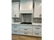 Modern kitchen with white cabinets, black hardware, marble countertops, and stainless steel range hood at 1111 Lake Varner Dr, Covington, GA 30014