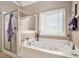 Bright bathroom with a white soaking tub, glass enclosed shower, and a large window at 127 Courts Of Hampton, Hampton, GA 30228