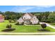 Aerial view of brick home with lush lawn, mature trees, and established landscaping on a sunny day at 127 Courts Of Hampton, Hampton, GA 30228