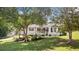 A beautiful exterior of a cozy, white house with a front porch nestled amongst mature trees in a lush, green yard at 2675 Springside Ct, Douglasville, GA 30135