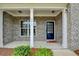 Cozy front porch with brick facade, white columns, and a welcoming black front door at 5215 Wheeler Run Dr, Auburn, GA 30011