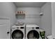 Bright laundry room featuring modern, white front load washer and dryer with a shelf above for storage at 5215 Wheeler Run Dr, Auburn, GA 30011