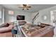 A spacious living room is furnished with leather sofas, a ceiling fan, and a staircase at 5215 Wheeler Run Dr, Auburn, GA 30011