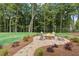 Landscaped fire pit with stone surround, chairs, hardscaped path, and lush greenery at 410 Beacon Way Way, Villa Rica, GA 30180