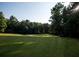 Sun dappled lawn view of community golf course surrounded by mature trees at 8145 Lakeview Pkwy, Villa Rica, GA 30180