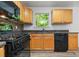 Sunlit kitchen featuring light wood cabinetry, black appliances, and a view at 503 Fable Ln, Canton, GA 30114