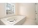 Bathroom with large soaking tub, a window with blinds, and tiled accents at 5633 Southland Dr, Stone Mountain, GA 30087