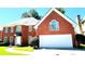 Classic brick home boasts a spacious two-car garage and a beautiful front lawn on a sunny day with ample parking at 5633 Southland Dr, Stone Mountain, GA 30087