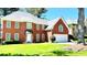 Charming brick home featuring a well-manicured lawn and attached two-car garage with a lovely tree in the front yard at 5633 Southland Dr, Stone Mountain, GA 30087