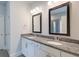 Bathroom featuring dual sinks with granite countertops and modern fixtures, framed mirrors, and tiled floors at 7570 Rambling Vale, Cumming, GA 30028