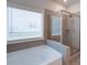 Bright bathroom showcasing a soaking tub, a glass-enclosed shower, and a window with natural light at 7570 Rambling Vale, Cumming, GA 30028