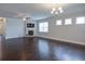 Open living room featuring dark hardwood floors, a fireplace, and a modern chandelier lighting fixture at 7570 Rambling Vale, Cumming, GA 30028
