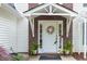 Close up of front door with decorative wreath, red brick accent, and matching planters at 2101 Emerald Dr, Loganville, GA 30052