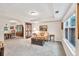 Inviting living room featuring neutral carpet, tray ceilings, large windows, and an archway to the dining area at 2101 Emerald Dr, Loganville, GA 30052