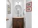 Compact powder room featuring a vanity with stone countertop, oval mirror, and modern lighting at 2101 Emerald Dr, Loganville, GA 30052