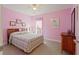 Bright pink bedroom featuring a bed with a colorful quilt, carpet floors, and ample natural light at 155 Edgewater Trl, Canton, GA 30115