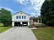 Charming two-story home featuring a front porch, two-car garage, and cars parked inside at 23 Jennifer Ln, Rydal, GA 30171